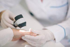Photo of a dermatologist examining hand under light