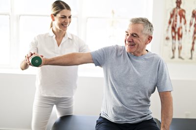 Photo of a female physical therapist assisting a patient with arm exercises