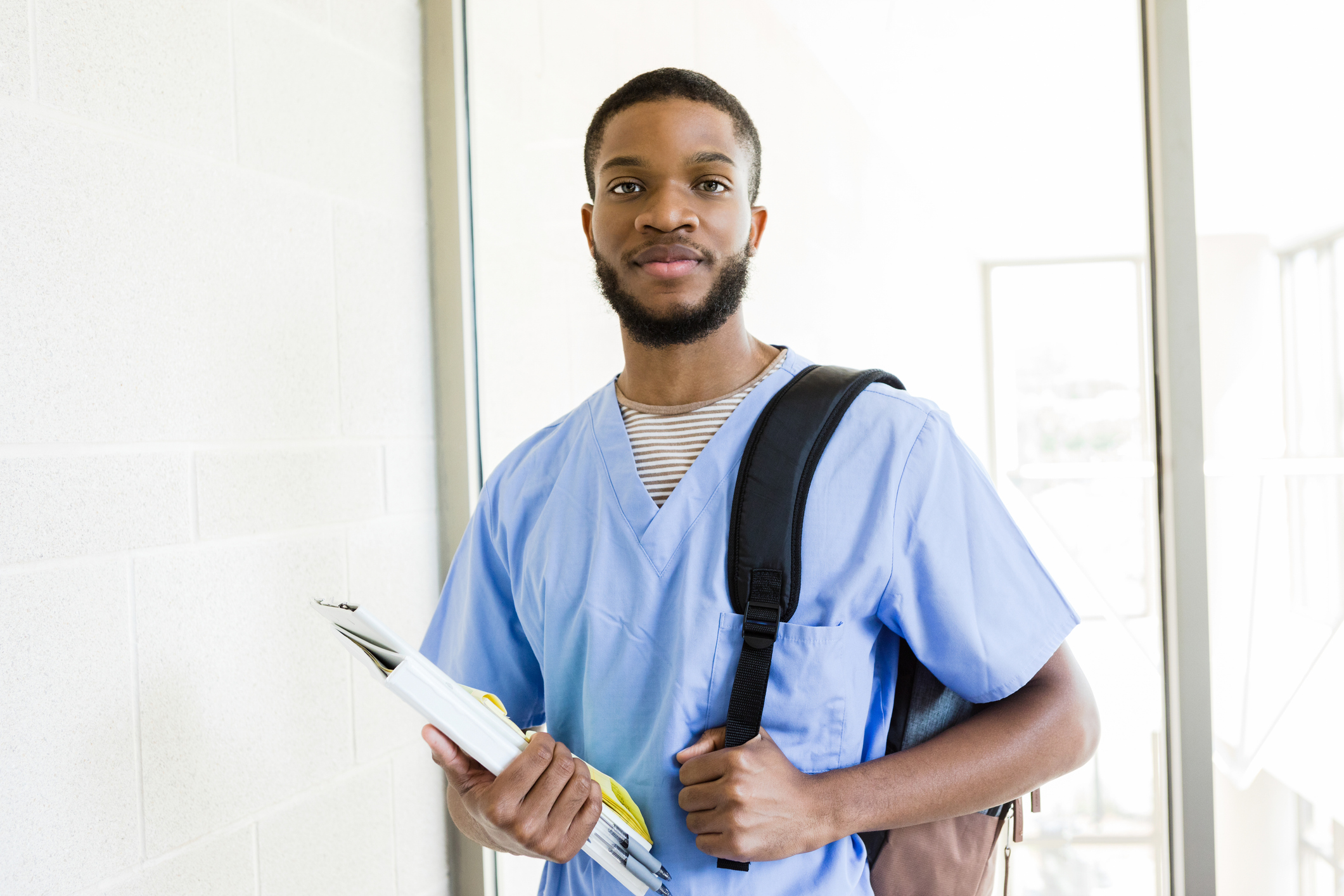student in scrubs with school supplies